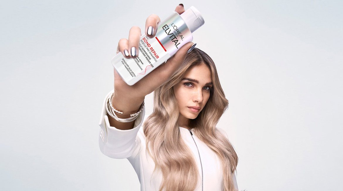 Frau hält Elvital Bond Repair Rescue Pre-Shampoo in der Hand